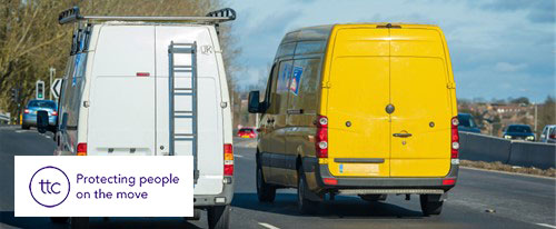 The back of two vans driving along a road